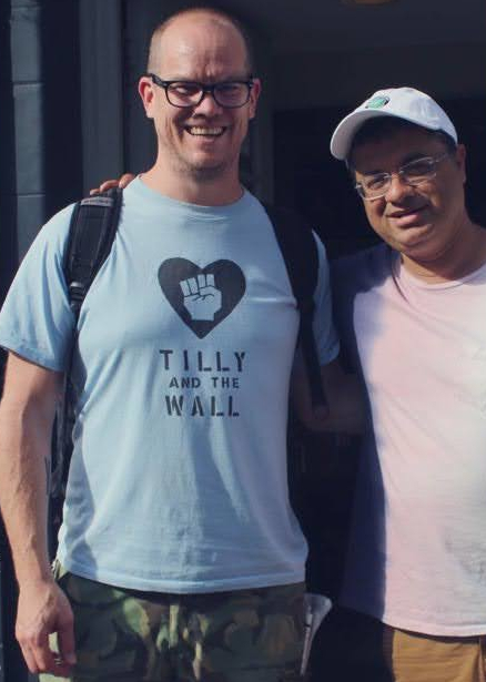 Travis Basevi, wearing a Tshirt showing a clenched fist in a heart-shape and the words 'Tilly and the Wall'. His friend Vishal Misra has his hand on Travis's shoulder