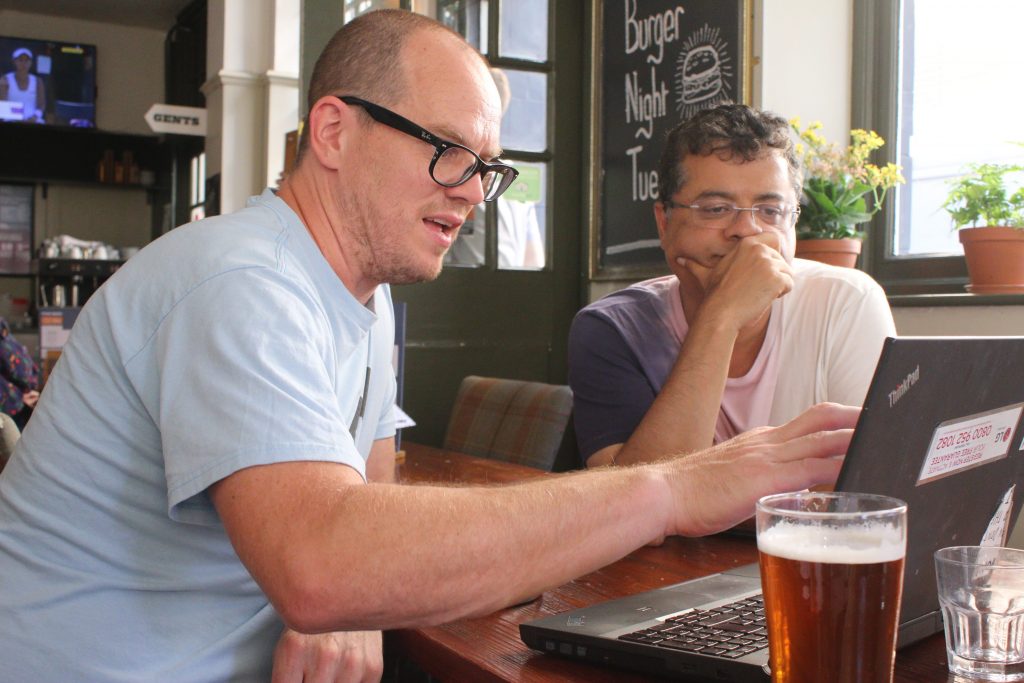 Travis Basevi and Vishal Misra, looking at a laptop